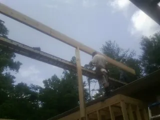 Carpenter setting a ridge beam over a new addition frame — Ice Dam Removal by Roofing Brothers in Reddick