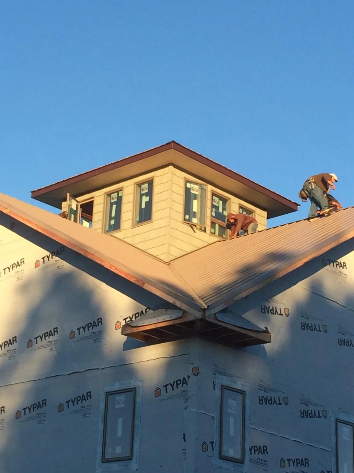 Roofers working around a rooftop cupola on a new metal roof at sunset — Roof Waterproofing in Reddick by Roofing Brothers